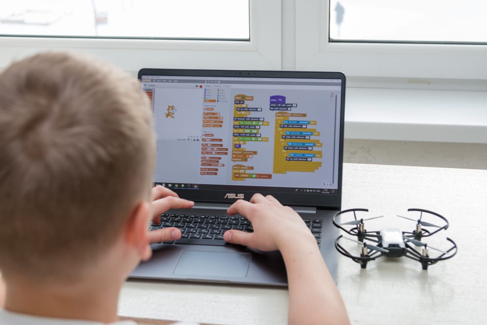 Students working on digital art landscapes and game design projects on computers in a classroom setting with an instructor.