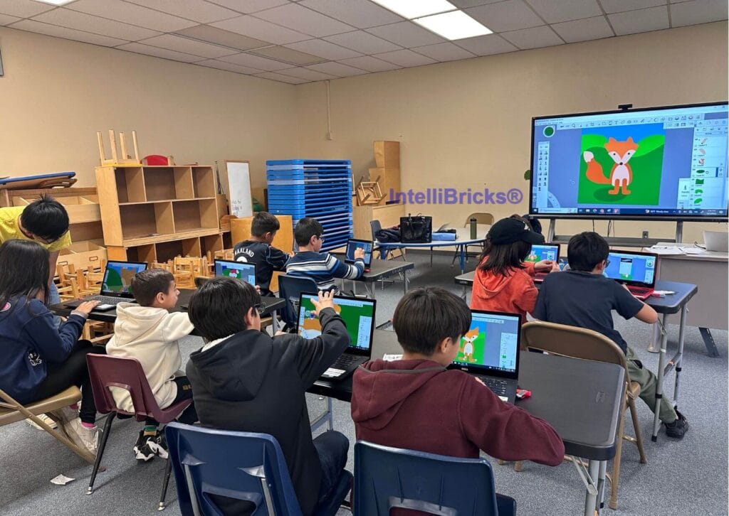 Creative Design in Action: A classroom of students utilizing individual laptops and an interactive smartboard to learn digital illustration and graphic design skills during a summer STEM session.