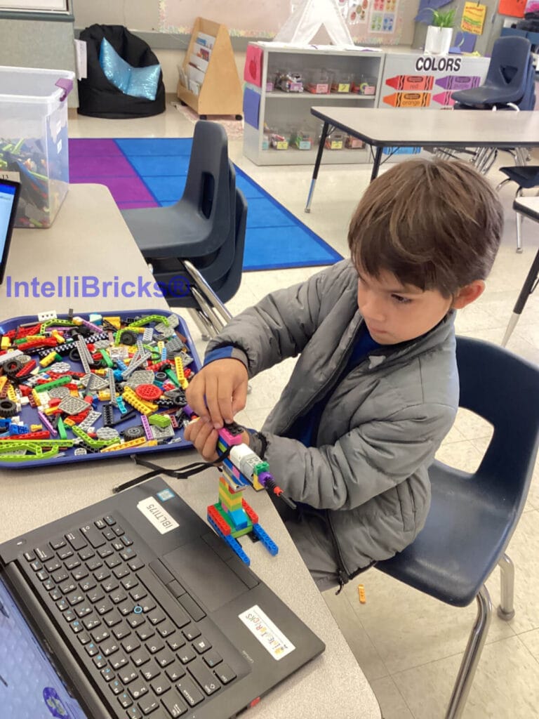 A young student constructing a LEGO power drill as part of a hands-on mechanical engineering design challenge.