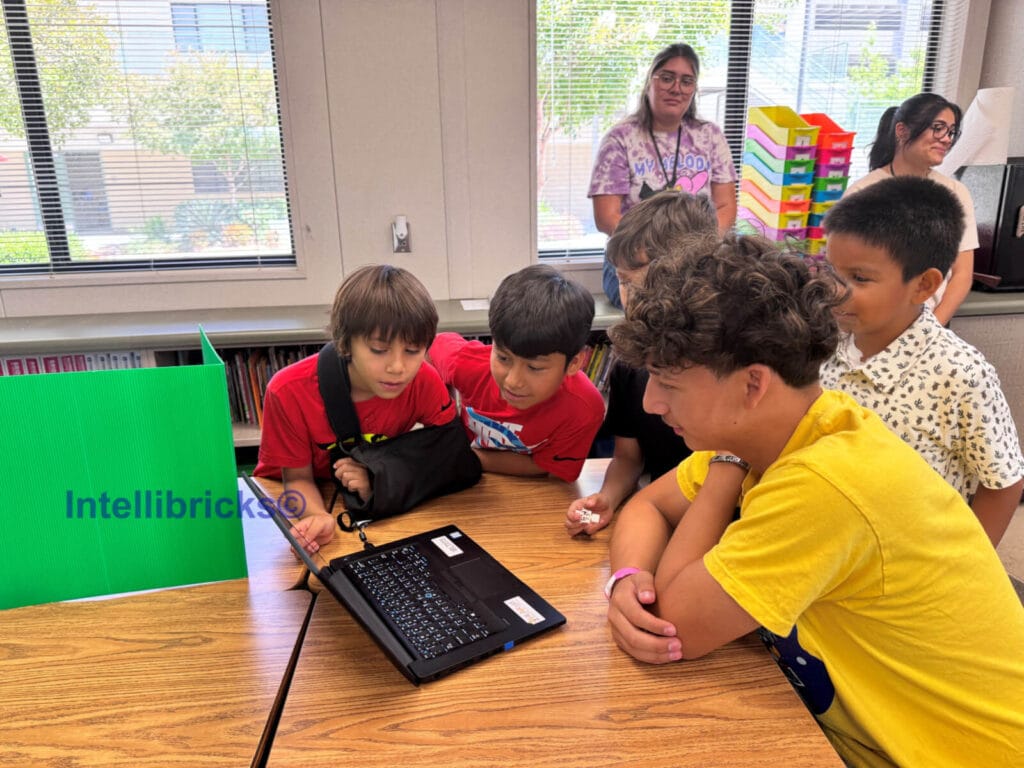 A group of students and an instructor gather around a laptop to watch a student-created stop-motion animation video at STEM camp.